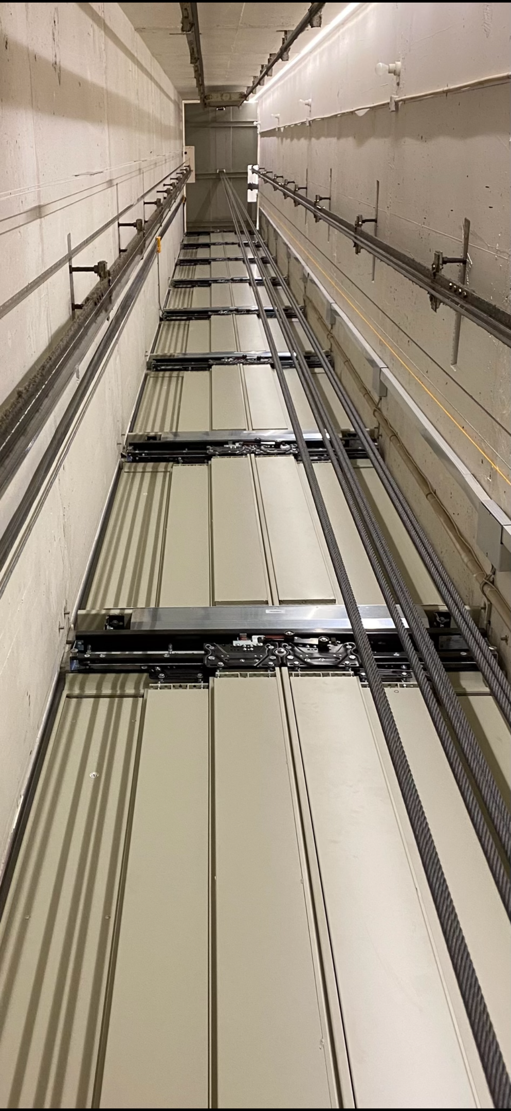 Specialist fixing or adjusting lift mechanism in elevator schaft. Regular repair, service and maintenance of elevator.