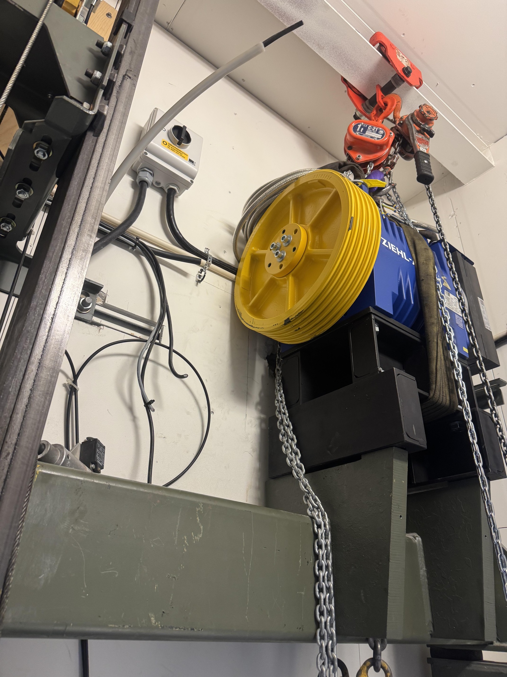Specialist fixing or adjusting lift mechanism in elevator schaft. Regular repair, service and maintenance of elevator.